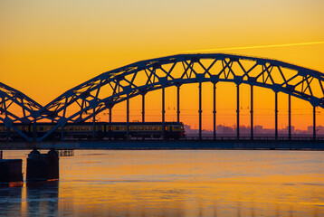 A beautiful sunrise scenery with iron bridge over the frozen river Daugava in Latvian capital city...