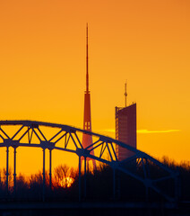 A beautiful sunrise scenery with iron bridge over the frozen river Daugava in Latvian capital city Riga. Winter landscape of Northern Europe.