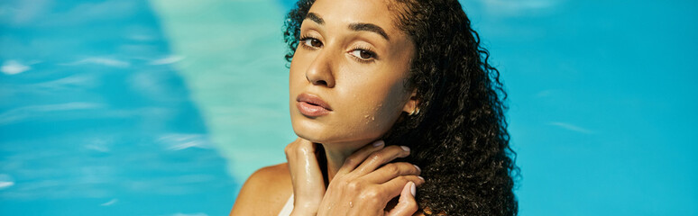 young black woman with wet curly hair standing cool blue pool water and looking at camera, banner