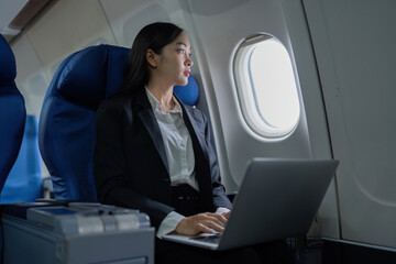 Fototapeta premium Beautiful Asian businesswoman working with laptop in aeroplane. working, travel, business concept