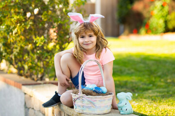 Fototapeta premium Happy Easter. Kids in bunny ears with Easter egg in basket. Boy play in hunting eggs. Spring holidays concept.