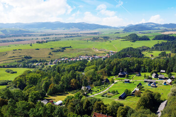 Fototapeta na wymiar picturesque landscape of the rural valley and farmland scenery of slovakia. village on the hill and mountains in the distance, view from above. bright sunny weather in summer