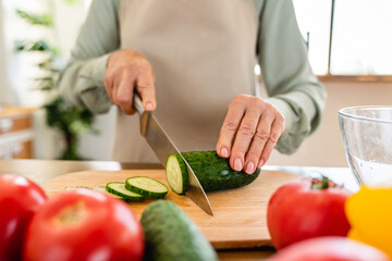 Cropped closeup photo of an old senior lady woman grandmother cutting vegetables for salad....
