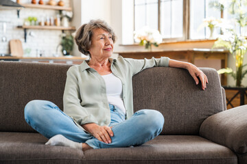 Old senior caucasian woman grandmother chilling relaxing resting at home on sofa couch while...
