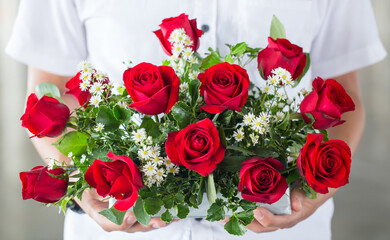 soft light tone with male hand giving bouquet of red roses