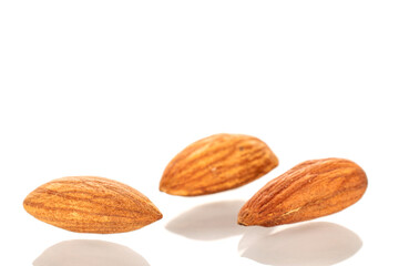 Several roasted almonds, macro, isolated on white background.