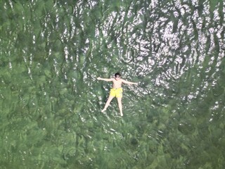 An aerial view of a person floating on top of a body of water surrounded by natural landscape, terrestrial plants, twigs, grasslands, trees, and a peaceful recreational setting - 750568288