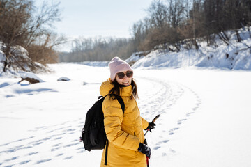 Fototapeta na wymiar Woman in glasses in nature on the background of snow, smiling, man with backpack traveling on snowy river.