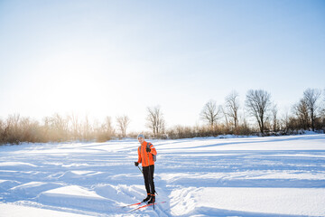 Skier standing on the snow against the background of the glare of the sun, training in the winter...