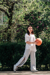 teenage girl playing basketball against a background of green foliage