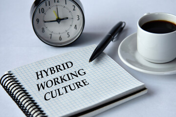 HYBRID WORKINGT CULTURE - words in a notebook on a white background with a clock and a cup of coffee