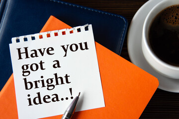 Have you got a bright idea..! - words on a white sheet of paper against the background of colorful notepads and a cup of coffee.
