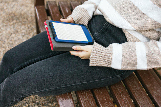 Person sitting on bench reading an e-book