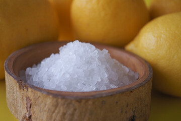 salt in a bowl and lemon on black yellow background 
