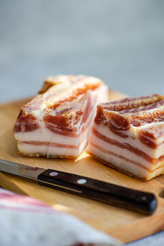 Sliced lard on wooden cutting board with knife