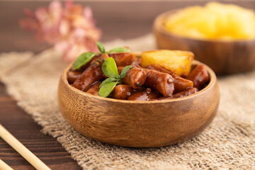 Tteokbokki or Topokki, fried rice cake stick, on brown wooden, side view, selective focus