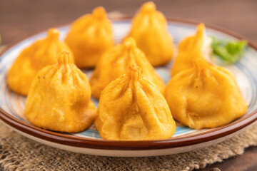 Manti dumplings with pepper, basil on brown wooden. Side view, selective focus