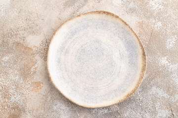 Empty blue and white ceramic plate on brown concrete background. Top view, copy space