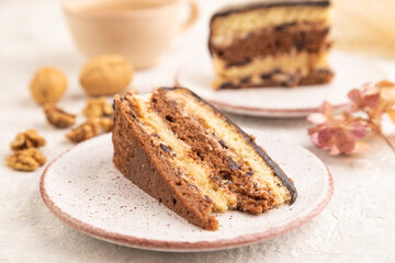 Chocolate biscuit cake with caramel cream and walnuts on gray concrete. side view, selective focus