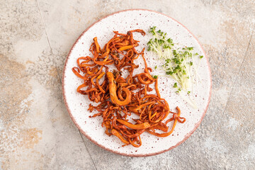 Fried Cordyceps militaris mushrooms on brown concrete. Top view, flat lay.