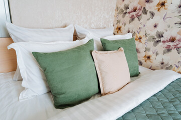 Rectangle bed with white linens, green pink pillows in creative arts pattern
