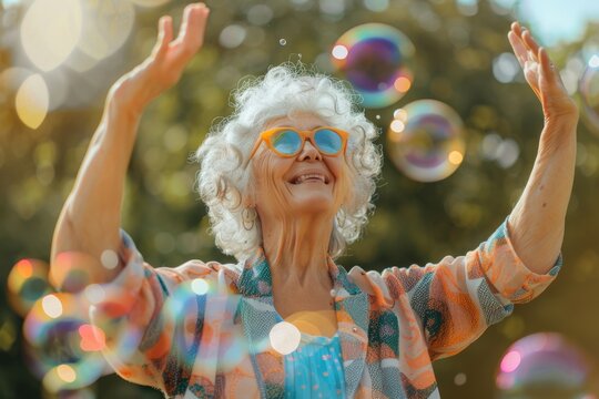 An exuberant senior lady with curly white hair raises her hands in delight, her bright orange sunglasses reflecting the soap bubbles around her in a sunny park.