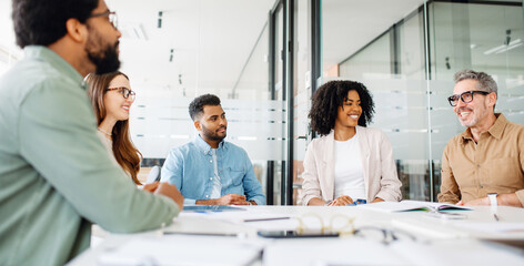 A diverse group of professionals is engaged in a lively discussion around a sleek, modern...