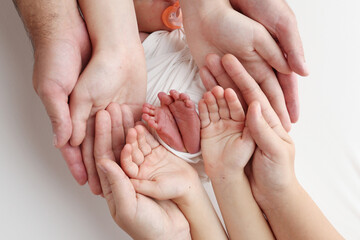 The palms of the father, the mother are holding the foot of the newborn baby in a white blanket....