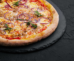 Pizza with tuna and red onion on stone cutting board