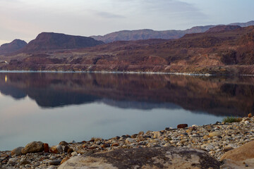 Rocky coast of Dead Sea. Jordan. Calm at Dead Sea after sunset. Reflection of rocks going into water. Rest and treatment.