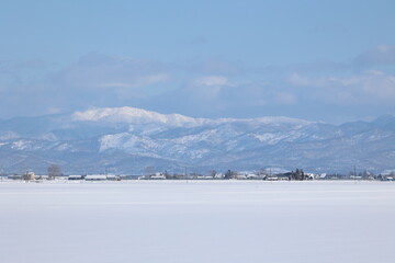 雪原と化した田畑の向こうにそびえる真白な山地