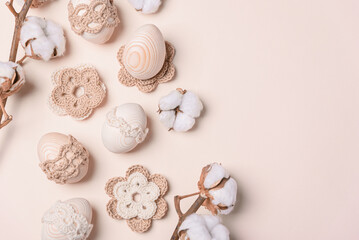 Craft eggs, knitted and cotton flowers on soft beige background. Top view. Copy space