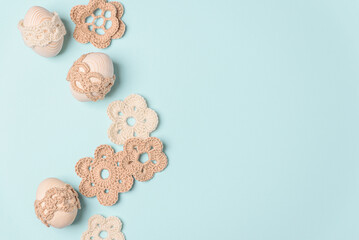 Craft knitted eggs and knitted flowers on blue background. Top view. Copy space
