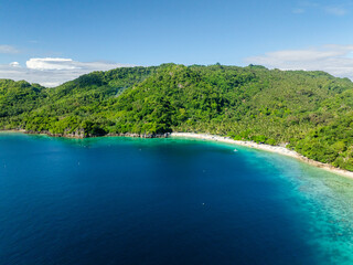 Fototapeta premium Coastline with boats over white sand beach. Alad Island with blue sea. Romblon, Philippines.