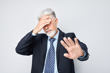 Senior businessman making stop gesture with arms crossed, signaling denial or restriction