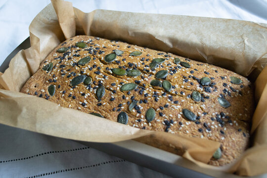 Hot homemade bread with sesame and pumpkin seeds on a white tablecloth, freshly baked in the oven . Gluten-free home baking concept, green buckwheat bread