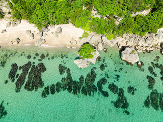 Carabao Island with rocks over white sand. Ocean waves and greenish sea water. San Jose, Romblon....