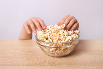 Children's hands are visible from under the table, trying to take popcorn from the table.