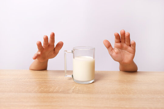 From under the table you can see the child's hands trying to pick up a glass of milk.