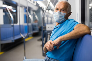 Fototapeta na wymiar Portrait of adult man in disposable mask traveling in subway train during daily