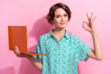 Photo of attractive person hold laptop demonstrate okey symbol approval isolated on pink color...