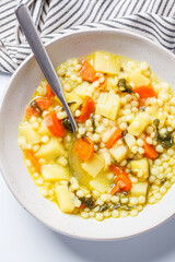 Israeli soup with ptitim, vegetables and spinach.