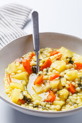 Israeli soup with ptitim, vegetables and spinach.