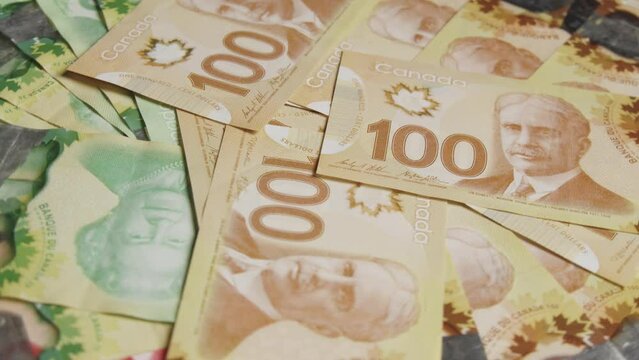 Many Canadian dollar bills are spinning in a circle, different currencies are scattered on the table. Canadian banknotes are banknotes or denominations of Canada.