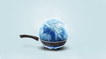 Planet earth burns in a frying pan on a gas burner on a blue background, concept. Global warming...
