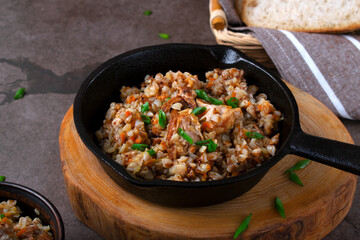 Meat with buckwheat served in the cast iron pan. Nutritious meal for lunch or dinner