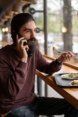 Hipster having lunch in a cafe or fast food restaurant, food on a tray, healthy eating, diet, calling on the phone during lunch break