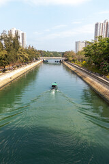 sailing boats on straight river  straight sidewalk  bridge cross river apartment building on left and right
Boat moored under the bridge