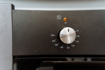 Close up of gas oven with silver knob, kitchen appliance in black circle