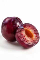 Whole and cut in half ripe plum with juicy inside, highlighted in white, the concept of freshness and natural benefits